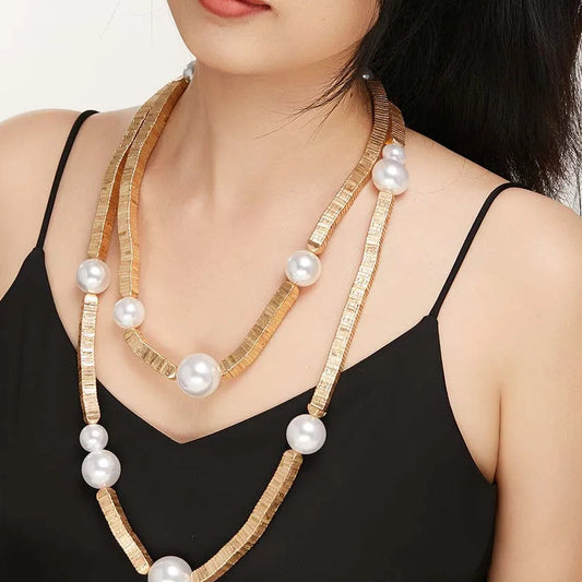 Woman wearing a long necklace with pearls and gold accents.