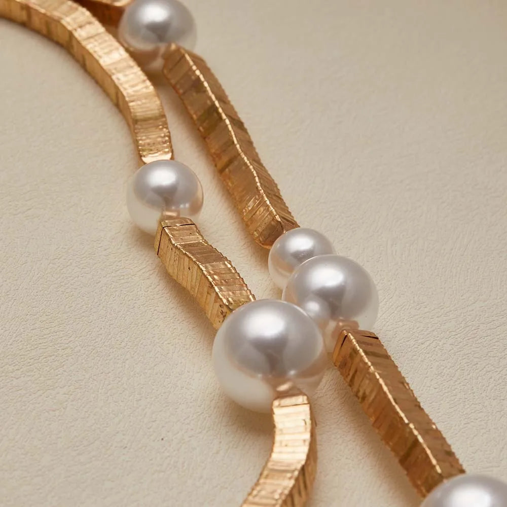 Gold bracelet with pearls on a beige background