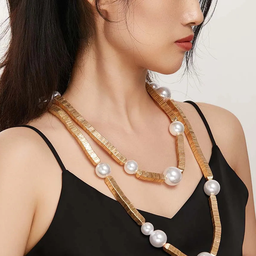 Woman wearing a gold and pearl necklace.