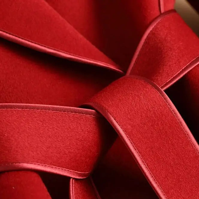 Close-up detail shot of a red textured fabric product with layered ribbon-like folds and a black text banner at the bottom containing Chinese characters.