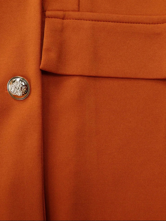Close-up of an orange-brown textured fabric garment with a silver decorative button and a 'Maisoor' brand watermark in the top left corner.