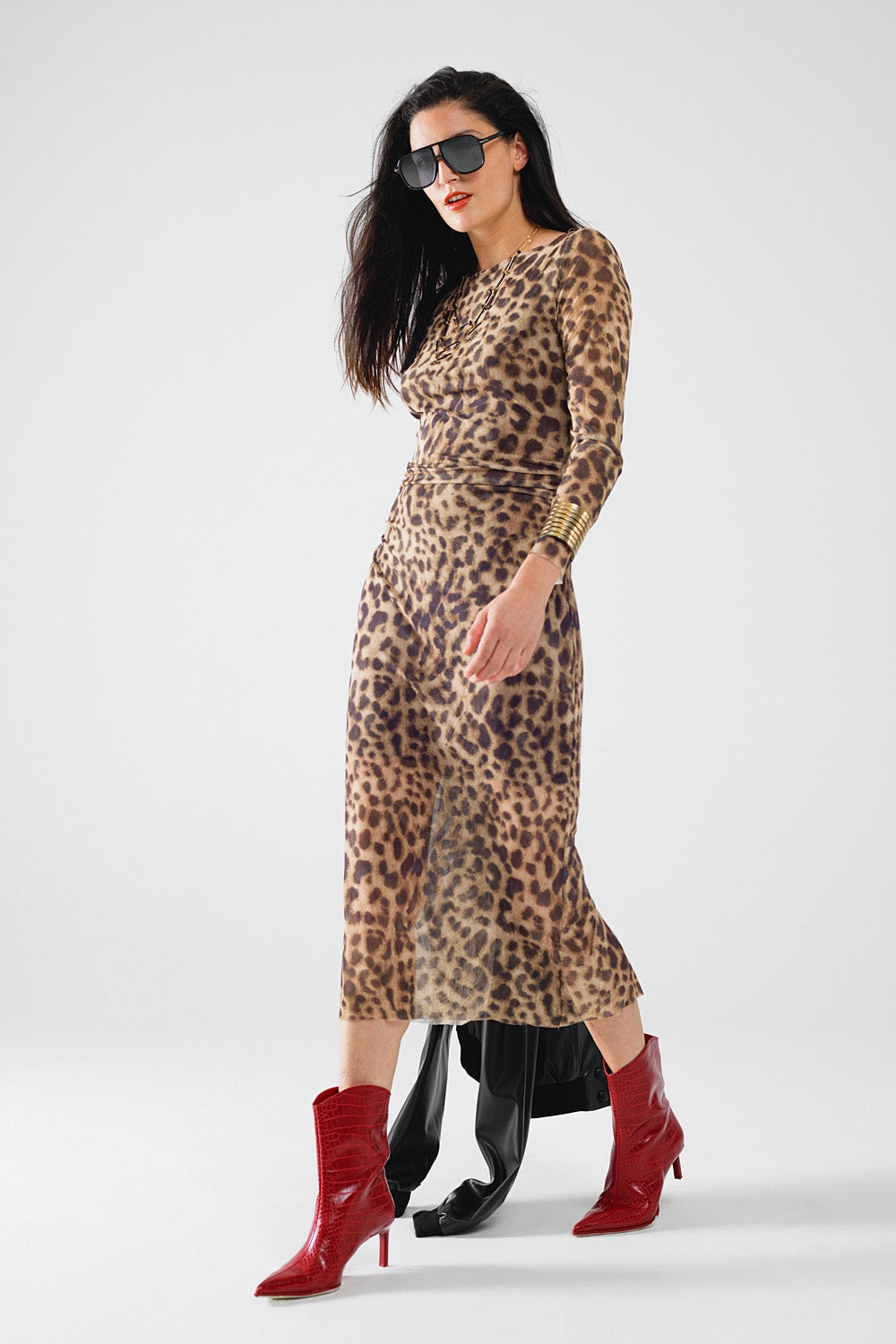 Woman wearing a leopard print dress with red boots on a white background